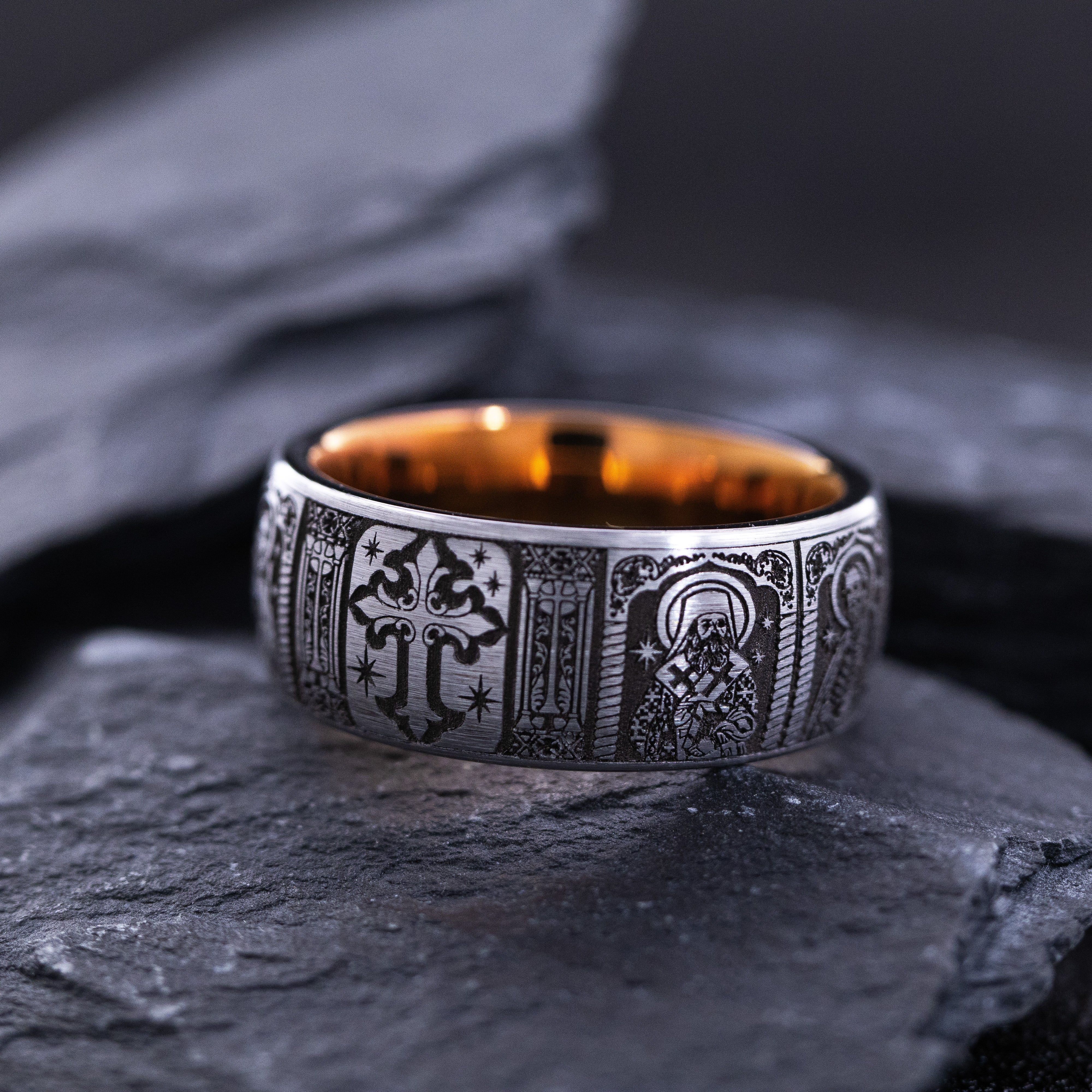 Silver ring with intricate designs on a dark stone surface