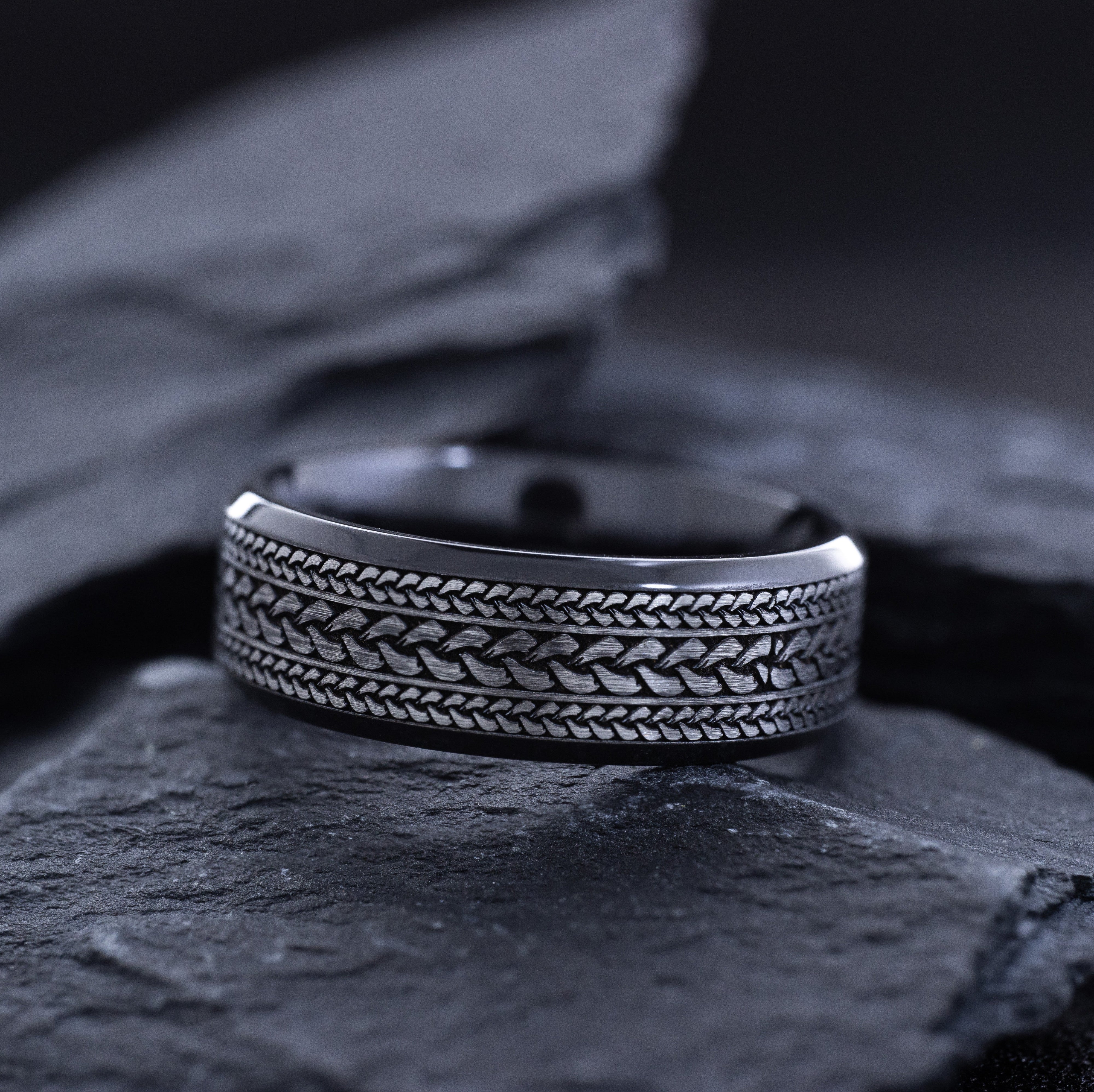 Silver ring with braided design on a dark stone surface